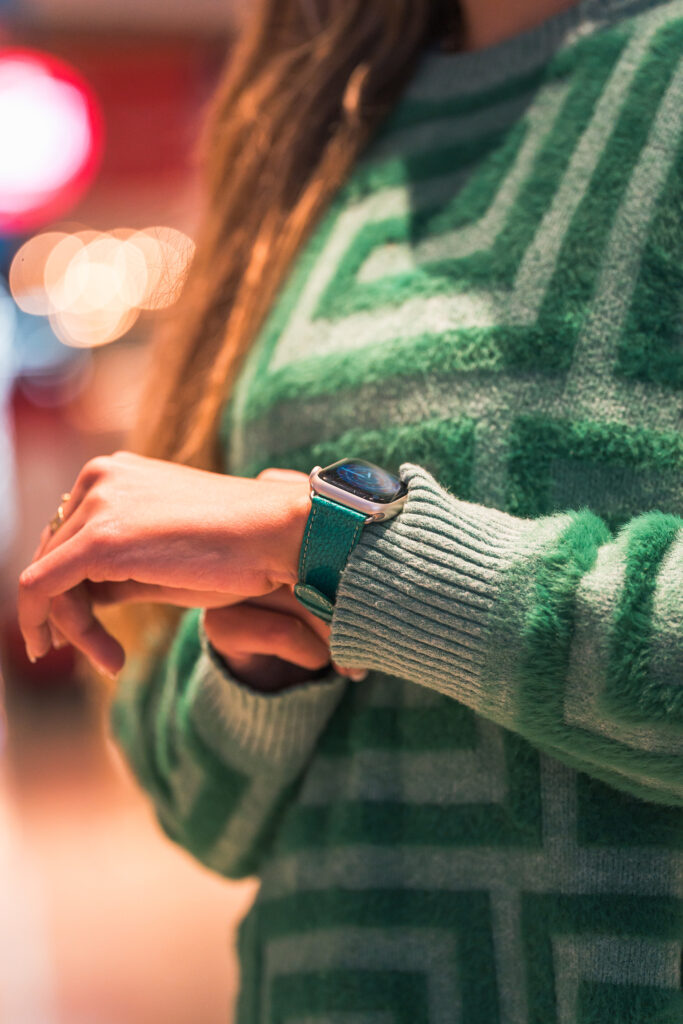 Femme avec un pull vert et une Apple Watch SE lumière stellaire avec un bracelet horizon vert Eternel